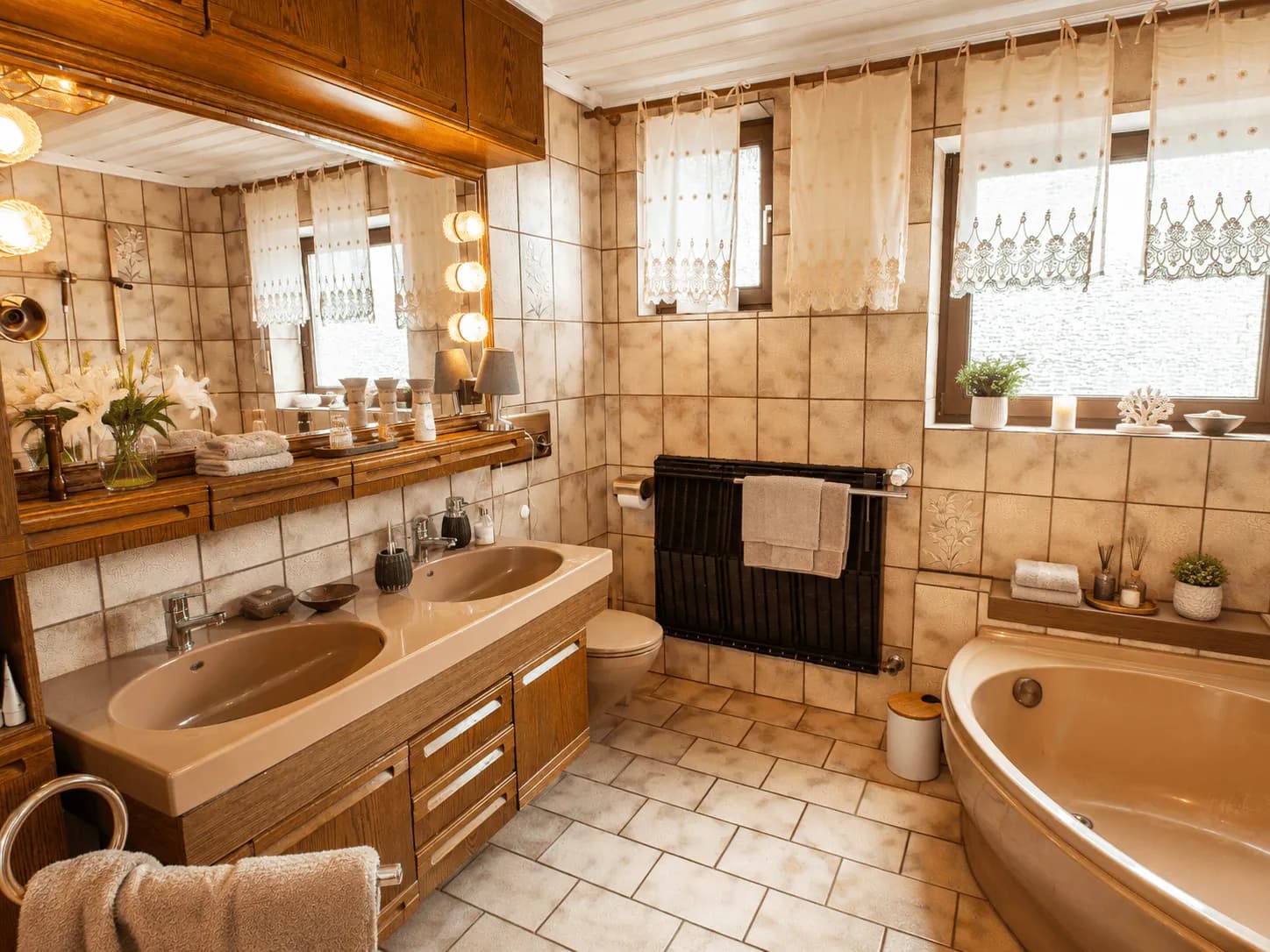 Geräumiges Badezimmer im warmen Landhausstil mit Doppelwaschtisch, Holzbadmöbeln, beleuchteter Spiegelwand und Eckbadewanne im Erdgeschoss in Burgkunstadt.