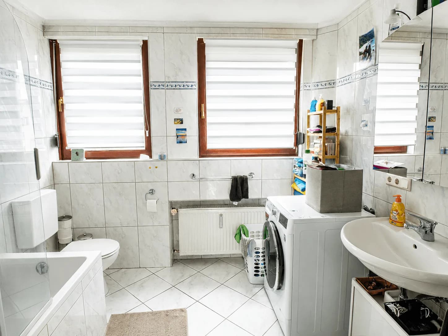 Hell gefliestes Tageslichtbad im Obergeschoss mit Badewanne, Waschbecken, WC, Waschmaschinenanschluss und zwei Fenstern mit Plissees in Burgkunstadt.