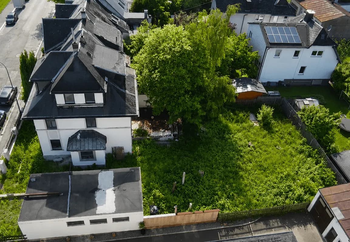 Luftaufnahme der Immobilie mit Wohnhaus, Flachdach-Nebengebäude/Garage und weitläufigem, grünem Gartengrundstück.