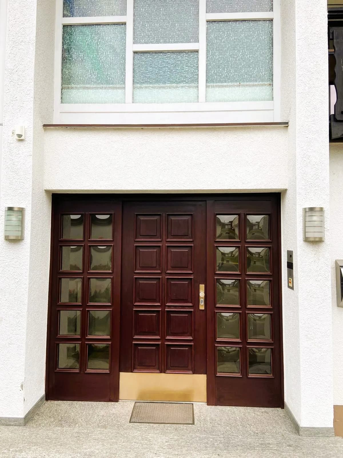 Weitwinkel-Luftaufnahme des Anwesens mit Ziegeldach, Kaminzug, Eckbalkon, Garage, weitläufigem Gartengrundstück mit Obstbäumen und bewaldeter Hügellandschaft im Hintergrund.