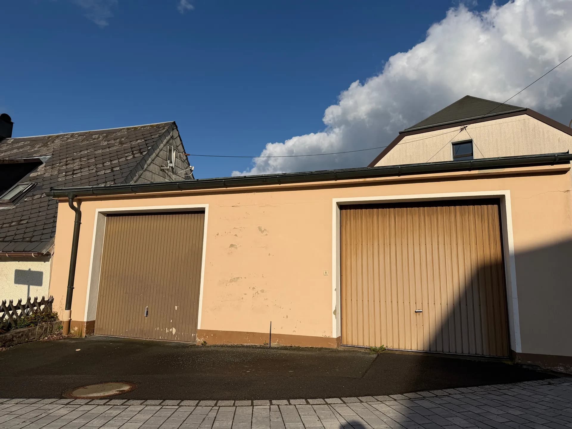 Massives Doppelgaragengebäude mit separaten Schwingtoren und befestigter Vorplatz-Zufahrt.