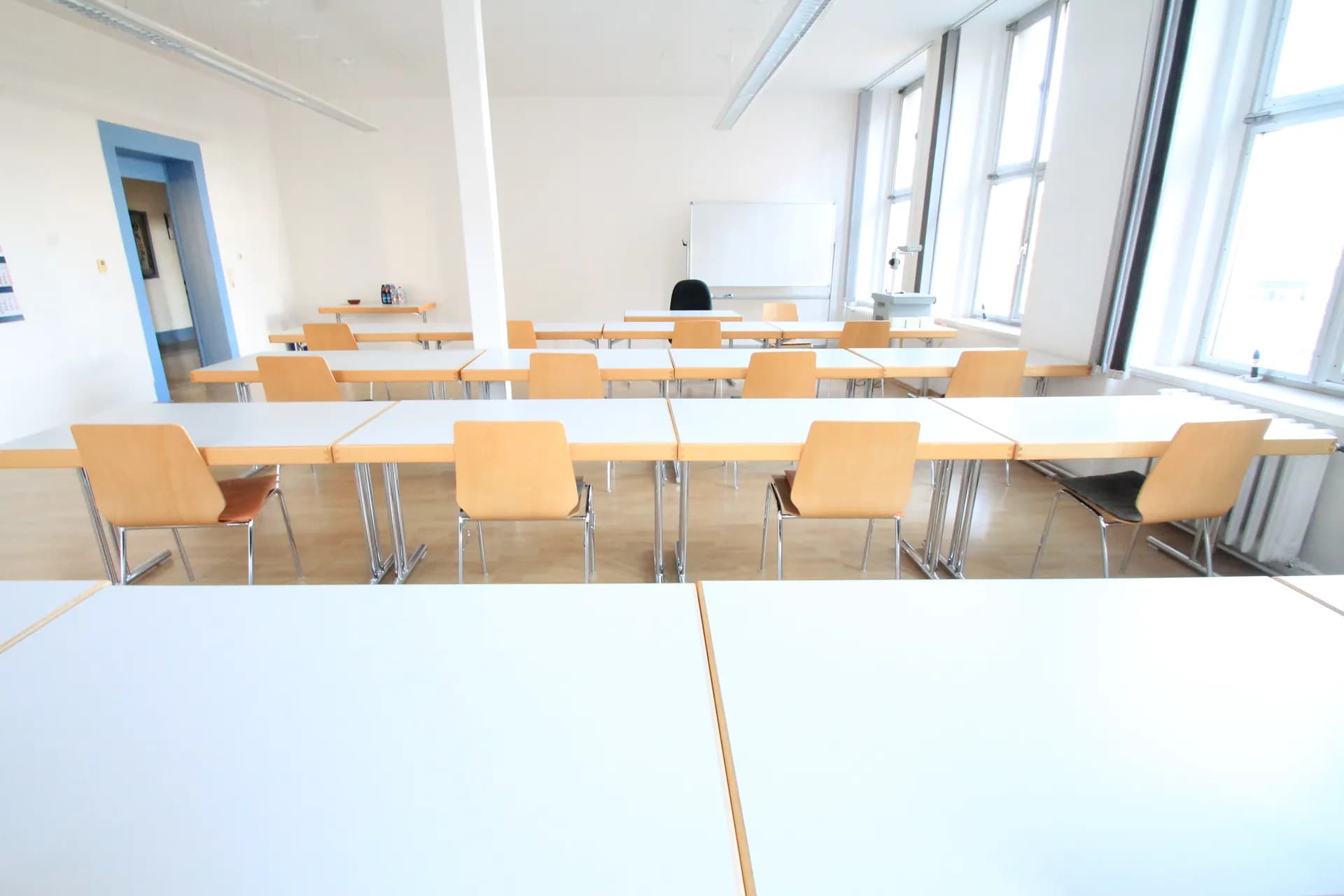 Schulungs- oder Seminarraum mit modularer Tisch- und Stuhlreihenbestuhlung, Whiteboard, hellem Bodenbelag und breiter Fensterfront.