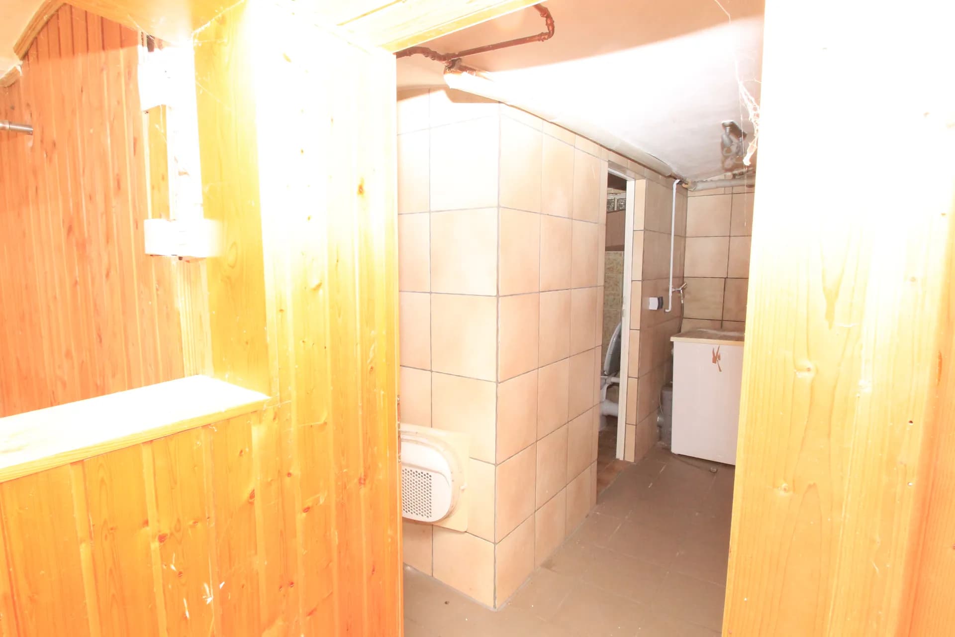 Untergeschossbereich mit Holzvertäfelung, gefliesten Wandabschnitten und separatem Sanitärbereich samt Waschmaschine.  IMG_5987.jpg