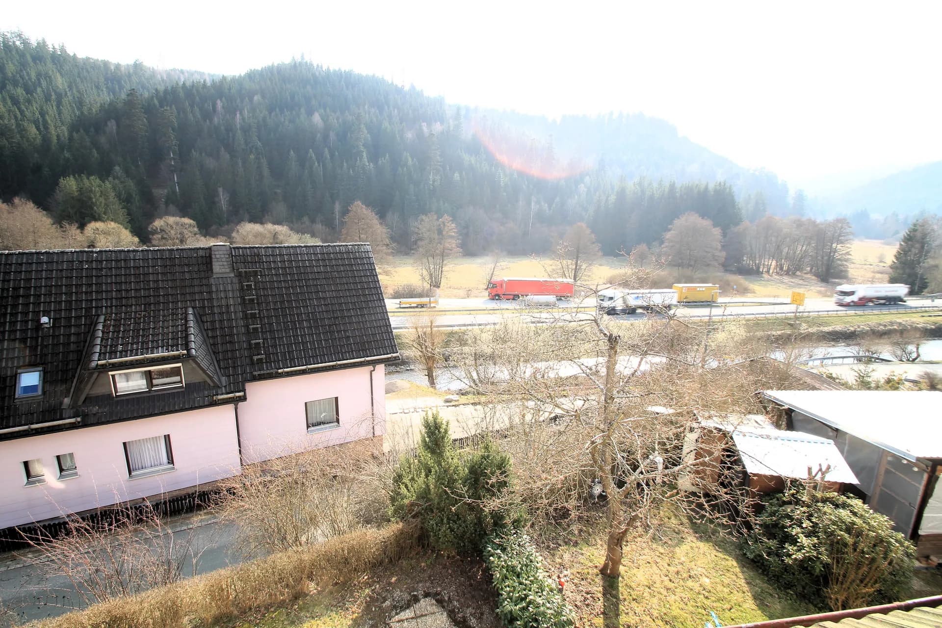 Malerischer Ausblick aus dem Obergeschoss über die grüne Tallage, bewaldete Hügel und das umliegende Wohngebiet.