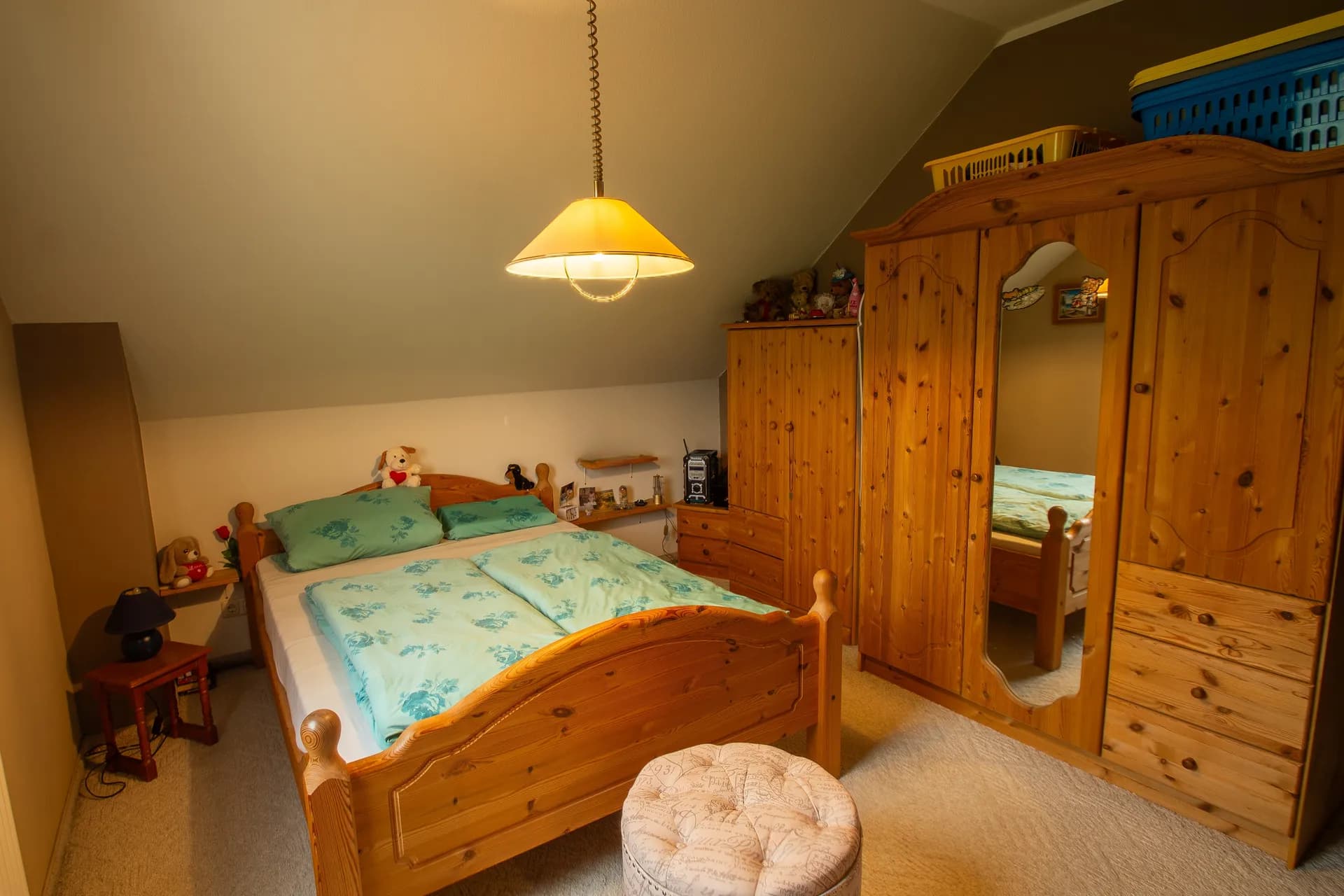 Gemütliches Schlafzimmer im Dachgeschoss mit Massivholzmöbeln, Doppelbett und großem Kleiderschrank.