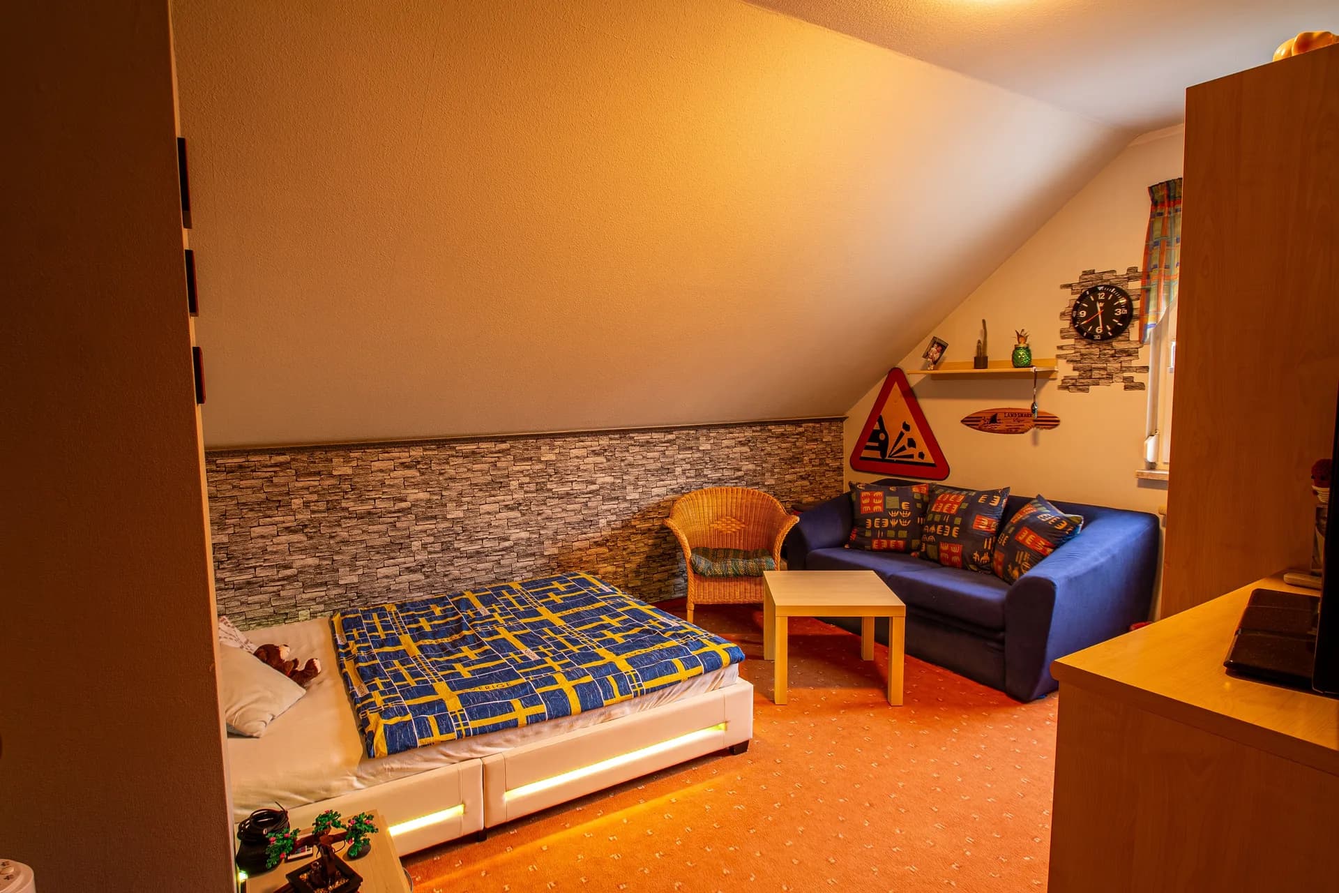 Schlafzimmer unter der Dachschräge mit rustikalem Holzmobiliar, Spiegelschrank und gemütlicher Beleuchtung.