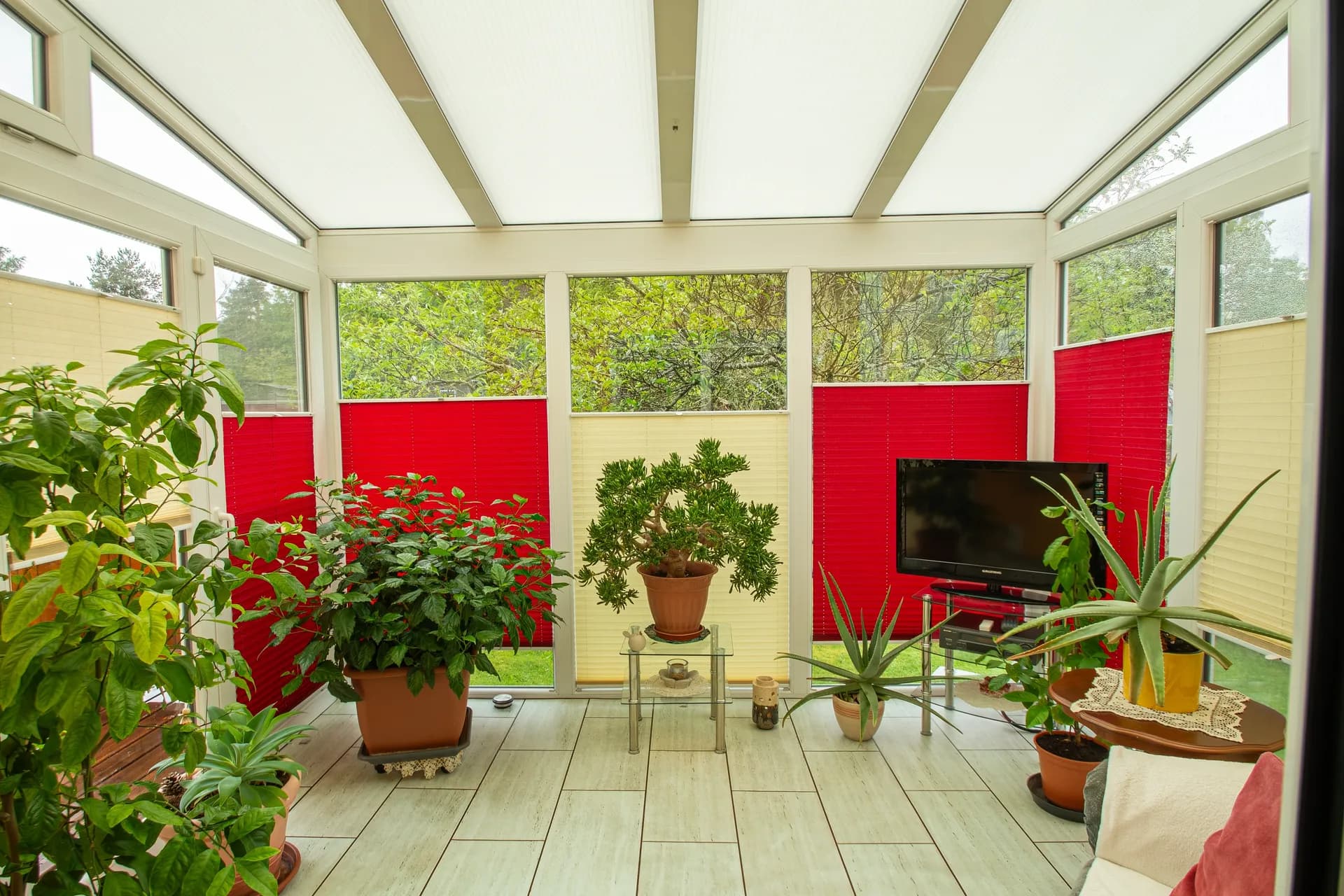 Großzügige Terrasse mit Fliesenboden, gemütlichem Sitzbereich und zahlreichen gepflegten Pflanzen in Töpfen und Kübeln.