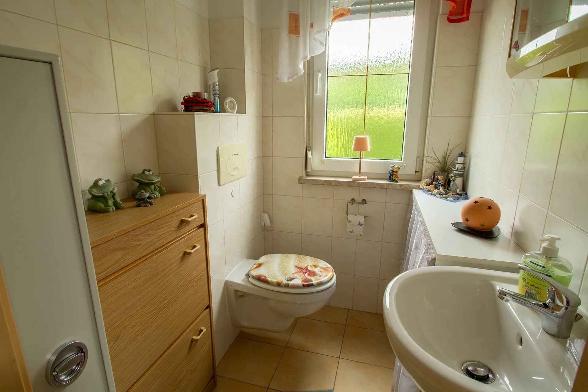 Kompaktes Gäste-WC mit wandhängender Toilette, Handwaschbecken und hellen Wandfliesen.
