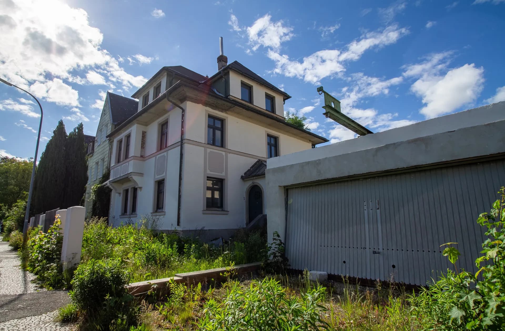 Außenansicht des Mehrfamilienhauses von der Straße aus mit vorgelagerter Großraumgarage und grünem Grundstück.