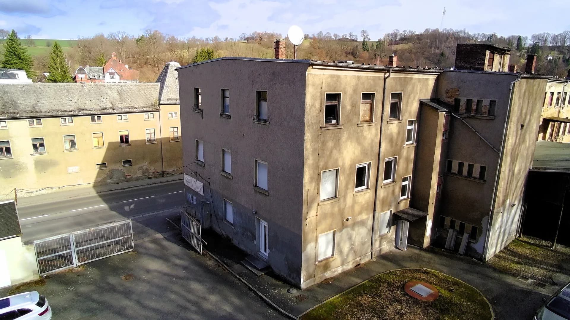 Perspektivische Außenansicht des mehrgeschossigen Gewerbebaus mit Flachdach, Satellitenanlage, Treppenhausanbau und asphaltierter Hoffläche.