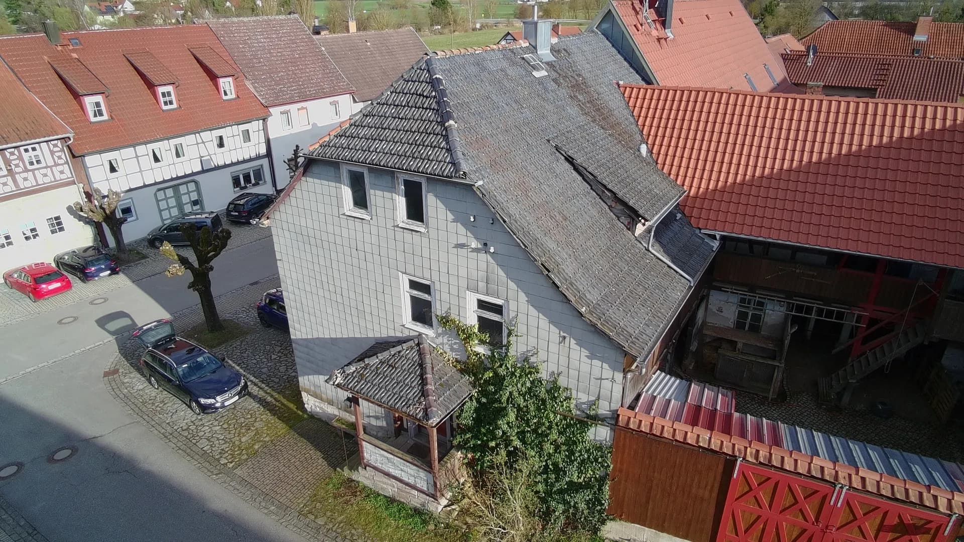 Luftansicht der Dachlandschaft des Hofensembles mit schieferverkleideter Fassade, geschütztem Innenhof, Nebengebäuden und straßenseitigem Hoftor.