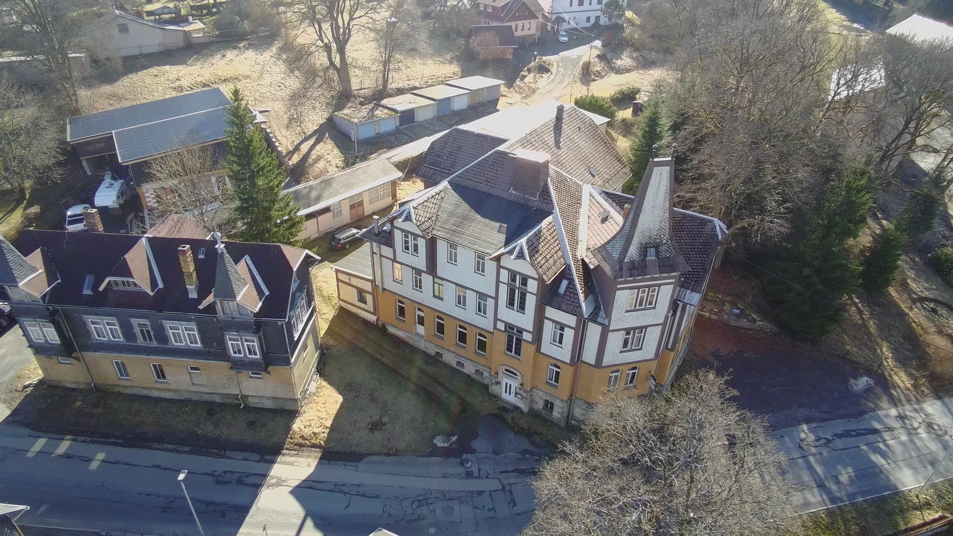 Übersichtsaufnahme des Ensembles aus Hotel „Schwarzaquelle“ und benachbarter Villa aus der Vogelperspektive mit Zufahrtsstraße, Waldrand und Außenflächen.
