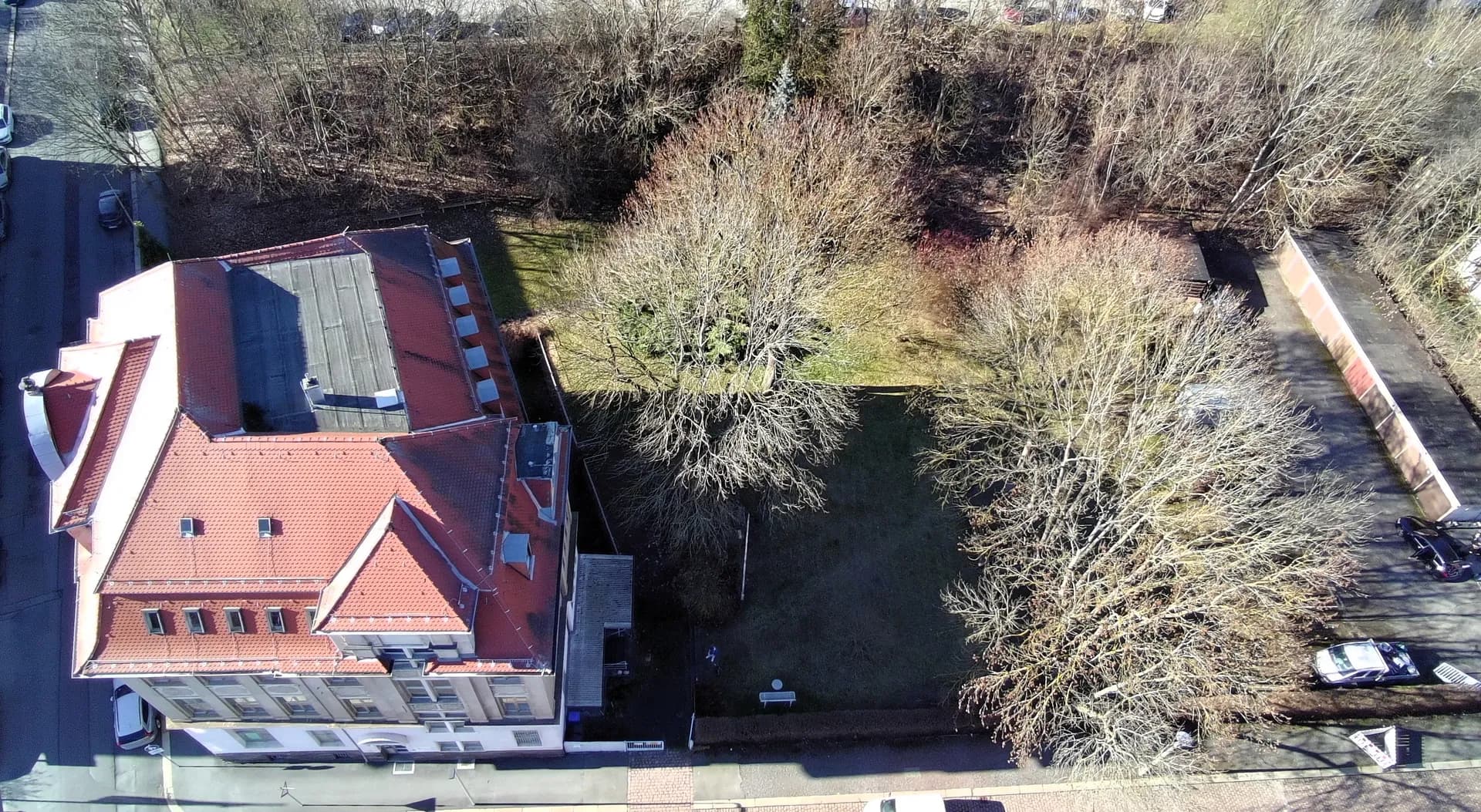 Vogelperspektive des gesamten Anwesens mit Dachlandschaft, Gauben, weitläufigem parkähnlichen Gartengrundstück mit Baumbestand und angrenzenden Garagenstellplätzen.