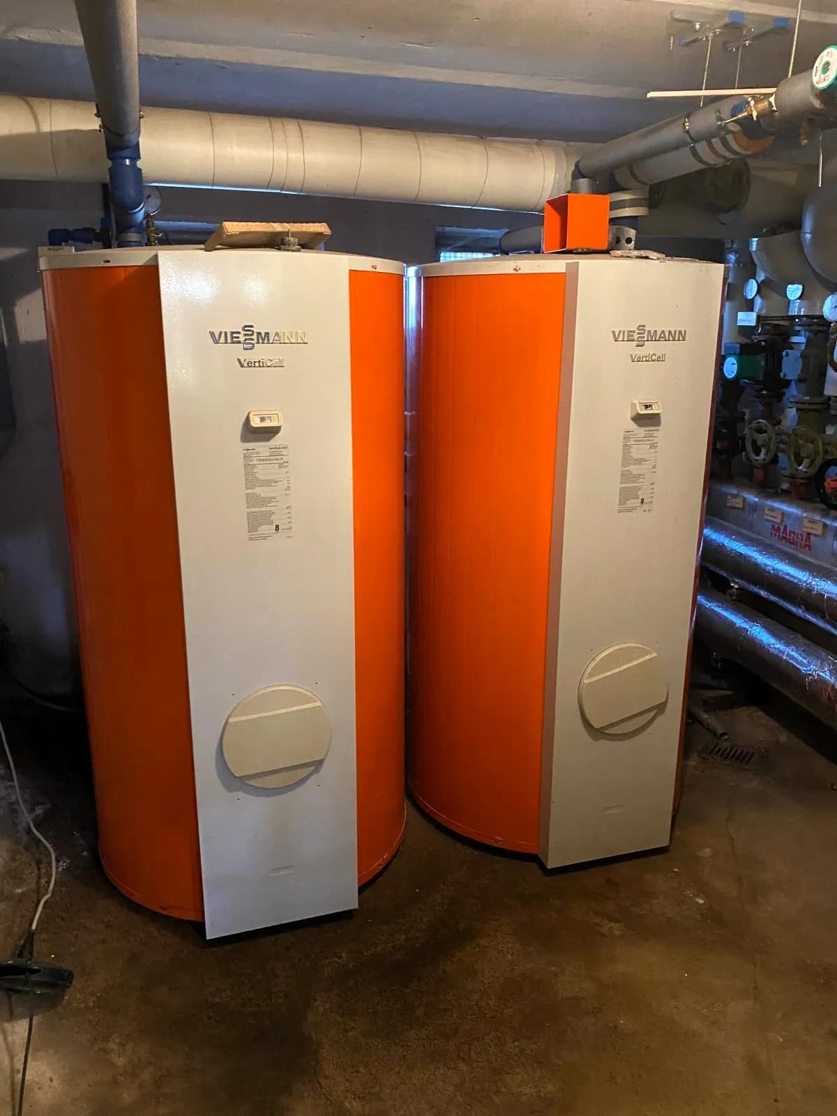 Heizungsraum eines Wohngebäudes mit zwei großen Viessmann VertiCell Warmwasserspeichern und verrohrter Heizanlage im Kellergeschoss.