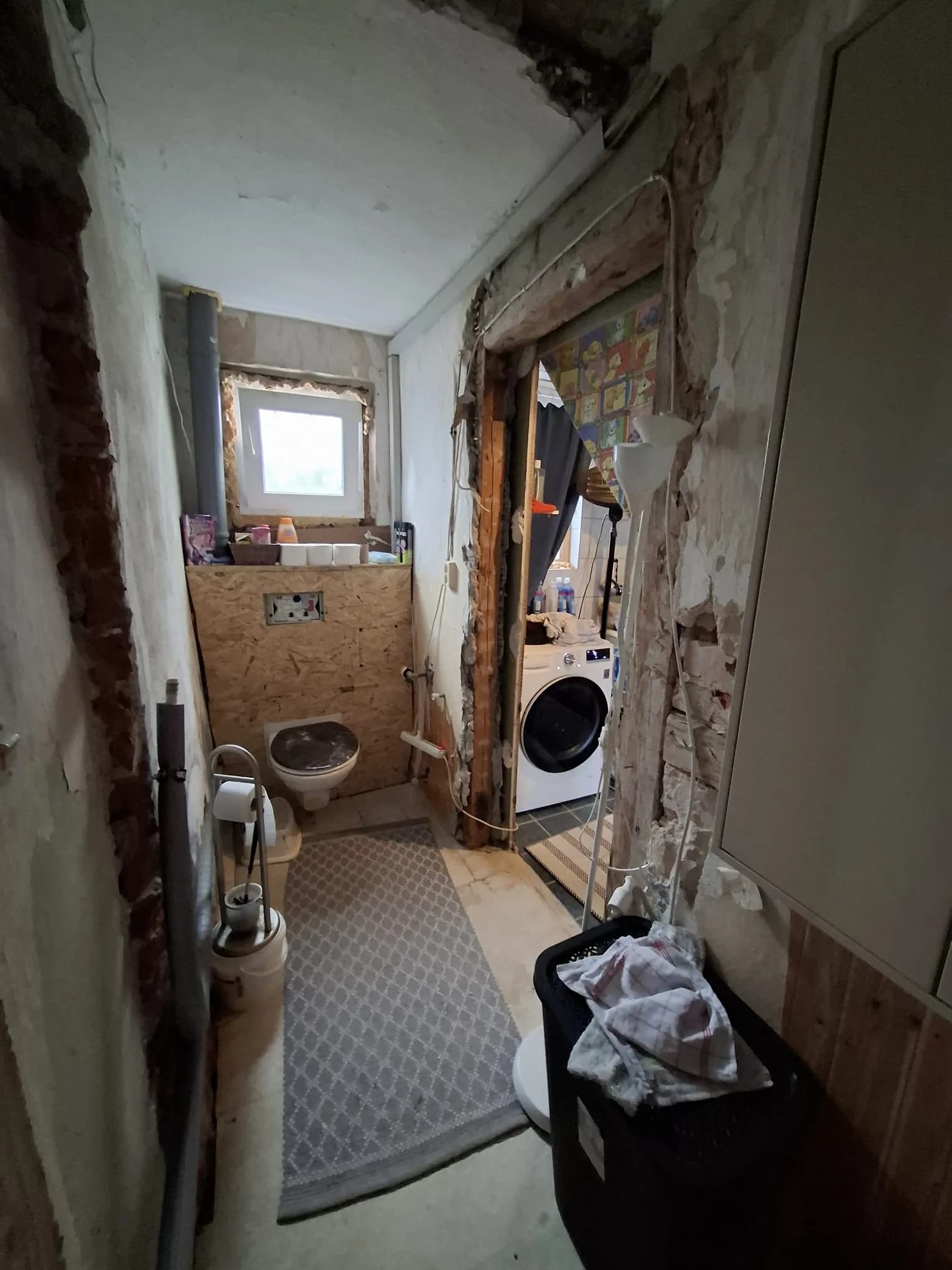 Gäste-WC im Sanierungszustand mit Vorwand-Installationssystem für ein Hänge-WC, Fenster und Durchgang zur Waschküche.