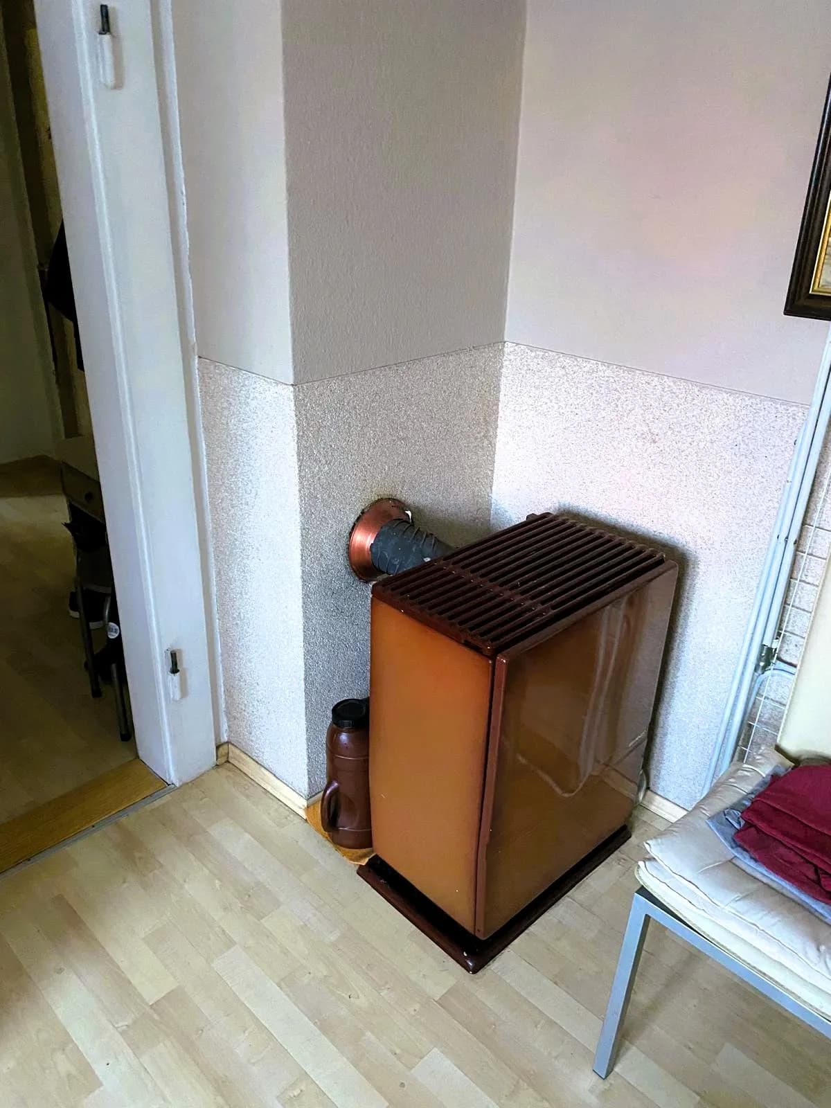 Wohnbereich mit separatem Ölofen und Kaminanschluss sowie hellem Laminatboden.