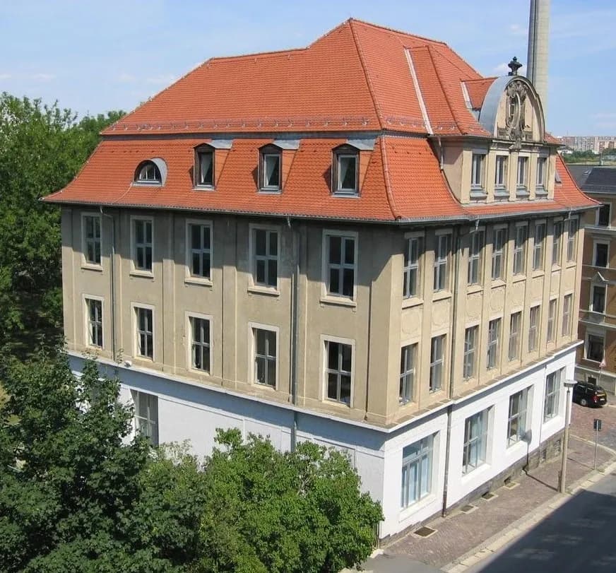 Repräsentative Eckansicht des historischen Mehrgeschosser-Gebäudes mit Ziegeleindeckung auf dem Mansarddach, Schmuckgiebel, Fledermausgaube und Natursteinsockel.