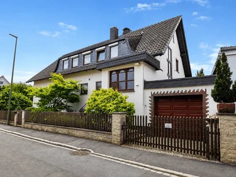 Gepflegtes Einfamilienhaus mit ausgebautem Mansarddach, angebauter Garage, Holzzaun und grünem Vorgarten: Straßenansicht in Burgkunstadt.