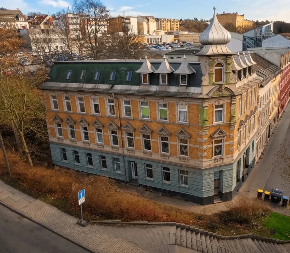 Prachtvolles historisches Eck- und Gründerzeitgebäude mit gelber Klinkerfassade, markantem Eckturm samt Haube und ausgebautem Mansarddach.